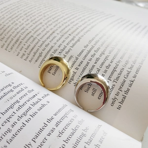 Close-up of gold and silver polished thick adjustable rings on open book pages