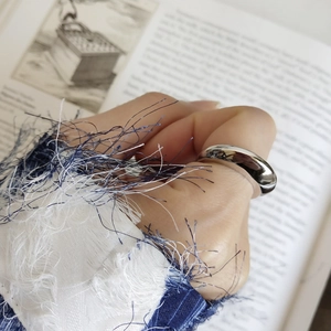 Polished silver ring detail on model finger with vintage book background and luxury finish