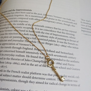Macro detail of a 925 sterling silver key necklace on a vintage art book background
