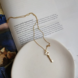 Macro view of vintage gold key pendant necklace on ceramic plate and art book