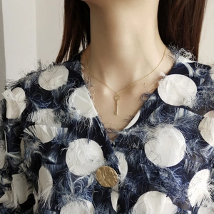 Close-up of a minimalist gold key pendant necklace worn on a model's neck for a trendy look