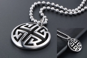 Detail of silver hollow round pendant necklace with geometric maze design and bead chain