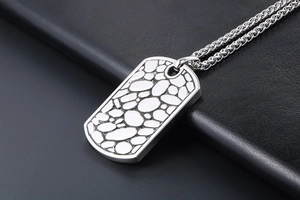 Macro shot of silver titanium dog tag necklace with pebble texture on black leather