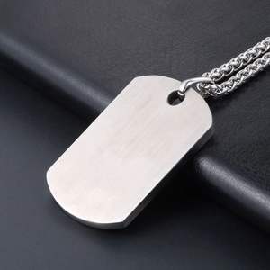 Silver brushed titanium steel dog tag necklace with pebble pendant on dark leather surface