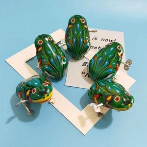 Detailed top view of five classic green wind-up tin frogs with colorful patterns