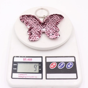 Sparkly double-sided pink sequin butterfly keychain on a white digital weighing scale