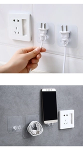 Close-up of transparent adhesive hooks for cable organization and wall plug storage