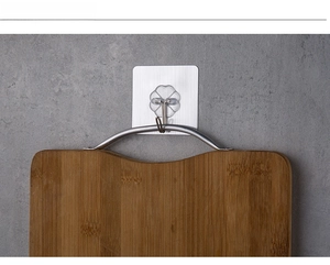 Strong adhesive transparent wall hook holding a wooden cutting board on a tile surface