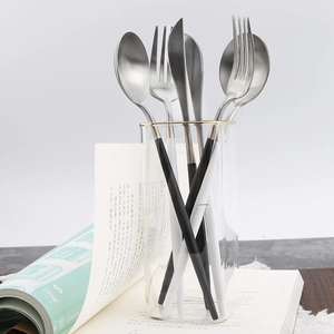 304 stainless steel cutlery set with black and white handles in a creative glass