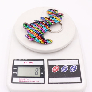 Sparkly multi-colored sequin rabbit keychain weighing 8g on a digital scale
