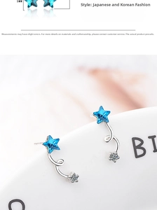 Macro view of blue star crystal earrings with spiral silver metal and tiny flower detail
