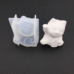 Detail of translucent silicone mold and white lucky cat plaster craft on black background