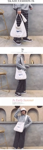 Close-up of white canvas tote bag with blue whale illustration and wide shoulder strap