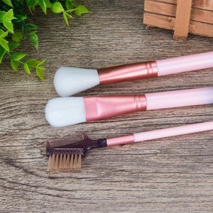 Detail of pink makeup brushes with rose gold ferrules on dark wood background