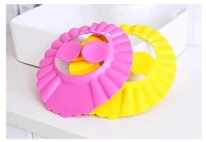 Close-up of pink and yellow adjustable baby shower caps on white sink edge