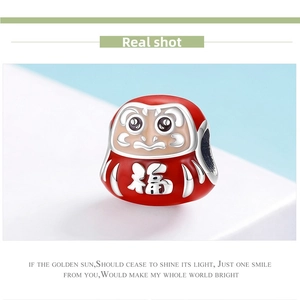 Macro shot of 925 silver Daruma charm with red enamel and lucky character engraving