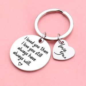 Polished stainless steel heart keychain with 'I love you still' engraving on pink background