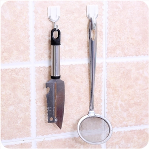 Stainless steel vegetable peeler and mesh strainer set hanging on a kitchen wall