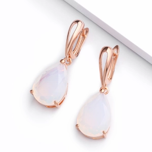 Detailed close-up of rose gold pear-cut opal drop earrings on a white display pedestal