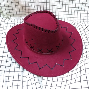Primer plano detallado de sombrero vaquero rojo con costuras negras sobre tela de ante