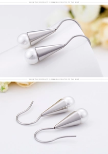 Detail of cone-shaped shell pearl drop earrings with minimalist silver metal hooks