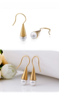 Detail of elegant gold cone-shaped earrings with white pearls in a minimalist design