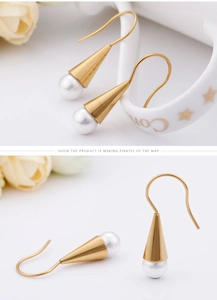 Detailed view of geometric gold cone earrings with round white pearls on floral decor