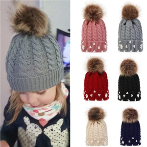 Detail of cable knit pattern and pearl embellishments on children winter beanies