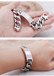 Macro shot of silver skull bracelet with zircon stones and stainless steel cuban chain