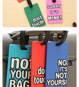 Detail of colorful PVC luggage tags with embossed slogans on bag and desk surface
