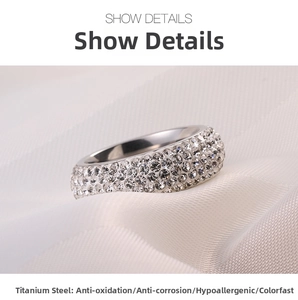 Detailed macro view of silver titanium steel ring with five rows of pavé crystals on white silk
