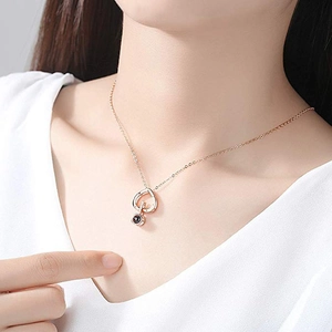 Elegant rose gold heart necklace with a round black projection stone on a female model
