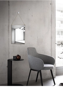 Close-up of golden hexagonal mirror with hanging chain on a minimalist concrete wall