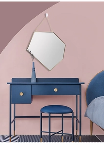 Close-up of a blue dressing table with gold handles and a modern hexagon wall mirror