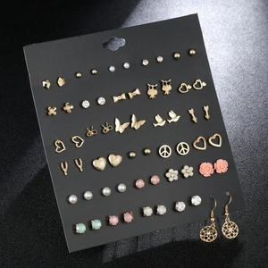 Collection of gold stud earrings featuring butterfly, heart, and pearl designs on a card