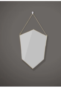 Close-up of golden brass shield-shaped mirror with a hanging chain on grey background