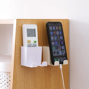 Close-up of wall-mounted plastic holder with dual hooks and bottom charging slot