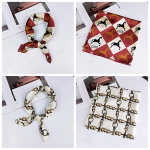 Detailed view of silk square scarves featuring red geometric and golden chain prints