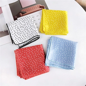 Polka dot silk square scarves in four colors arranged in a flat lay grid on white background