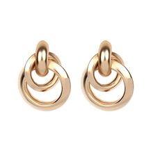 Détail des boucles d'oreilles entrelacées en métal doré avec d'élégantes perles fines
