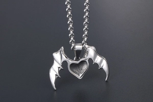 Macro detail of silver heart pendant with bat wings in Gothic punk style metal texture