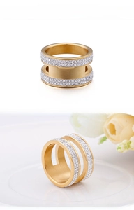 Détail d'une bague double dorée avec des strass blancs brillants et une finition brossée