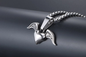 Detailed close-up of retro silver heart pendant with wings on a steel chain