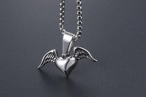 Detailed view of polished silver heart and angel wing pendant on a box chain necklace