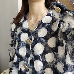 Detailed shot of 925 sterling silver coin pendant necklace styled on dot texture blouse