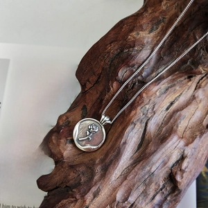 Detail of vintage 925 silver necklace with rose relief pendant on rustic dark wood background