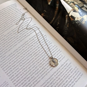 Detailed close-up of a vintage 925 silver rose pendant necklace on an open book page