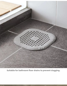 Vista dettagliata del filtro in silicone grigio per lavandino con gocce d'acqua sui pavimenti
