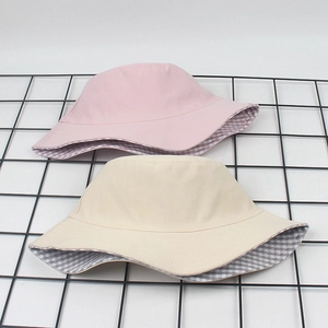 Detail of pink and beige cotton bucket hats with gingham lining on a black wire rack