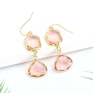 Detailed view of pink crystal teardrop earrings with gold plating on white background